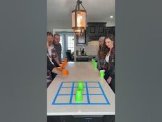 some people are standing around a table with cups on it and an object in the middle