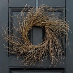 a wreath on the front door of a house that has been decorated with dried twigs