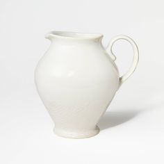 a white vase is sitting on a white surface with no one in the photo to describe it