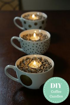 three coffee mugs with candles in them sitting on a table