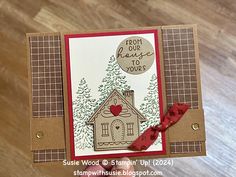 a close up of a card with a house on it and a red ribbon around the edge