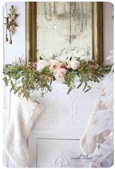 a fireplace decorated for christmas with stockings and flowers