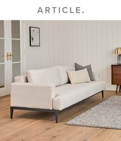 a white couch sitting on top of a hard wood floor next to a wooden table