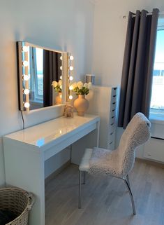 a white vanity with lights on it and a chair