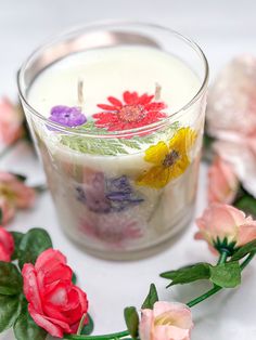 a small glass candle with flowers around it