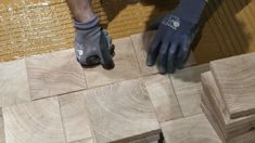 a person in blue gloves laying wood planks on the floor