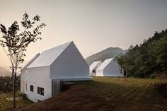 two white houses sitting on top of a hill next to each other with trees in front of them