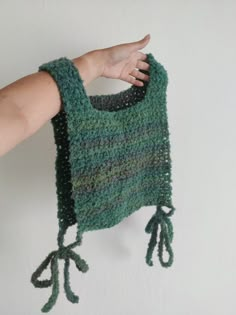 a hand holding up a green knitted scarf