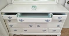 a white dresser with drawers and a mirror