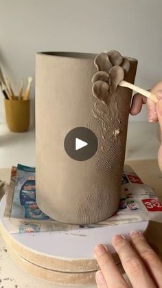 a person is making a vase out of clay with a toothpick in it