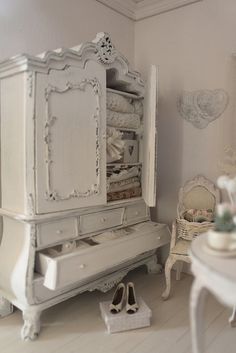 a white dresser sitting in the corner of a room next to a chair and table