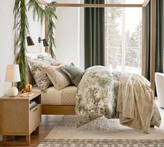 a bed sitting in a bedroom next to a window covered in green curtains and pillows