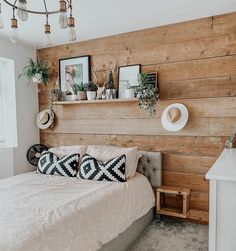 a bedroom with wood paneling and white bedding is pictured in this image, there are two hats on the headboard