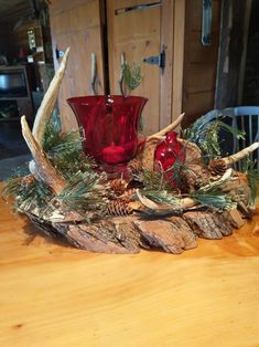 two red glass vases sitting on top of a wooden table next to antlers