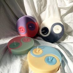 three colorful candles sitting on top of a white sheet