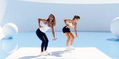 two beautiful women standing next to each other in front of a blue wall with white balls