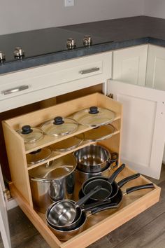 an open cabinet with pots and pans in it