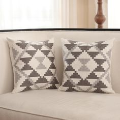 two pillows sitting on top of a white couch