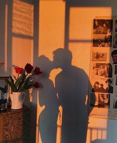 the shadow of a man standing next to a vase with flowers