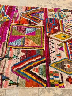 a multicolored area rug on the floor with various patterns and colors in it