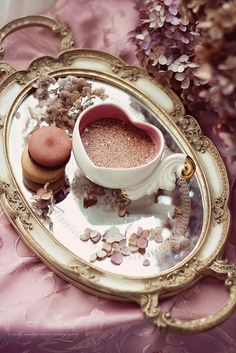 there is a cup and saucer on the tray with flowers in it, next to some cookies