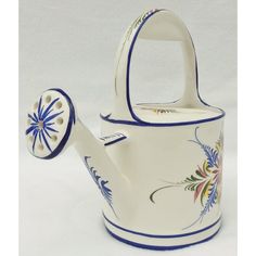 a white tea pot with blue trim and flower design on the outside, sitting next to a ceramic watering can