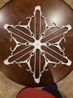 a person standing next to a wooden table with an intricate design on the top and bottom