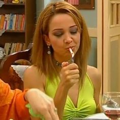 the woman is brushing her teeth while sitting at the table in front of wine glasses