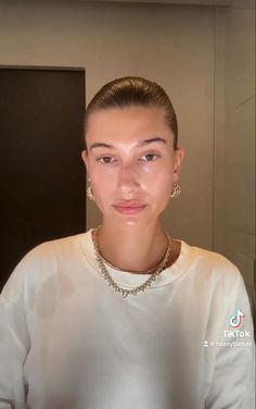 a woman in a white shirt is looking at the camera and she has earrings on her head