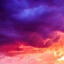 an airplane flying in the sky at sunset or sunrise with purple and red clouds above it