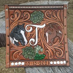 two horses are depicted in the center of this hand tooled leather name plate with succulents