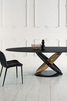 a modern dining table with black chairs and a glass top, in front of a white wall