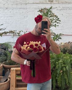 a man taking a selfie with flowers in front of him holding a cell phone