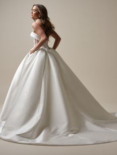 a woman in a white wedding dress posing for the camera with her hands on her hips