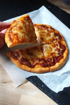 a person cutting into a pizza on top of a piece of wax paper with a knife