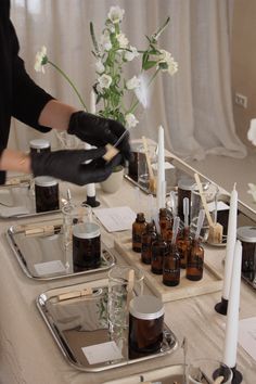 a table topped with lots of bottles filled with liquid next to candles and vases