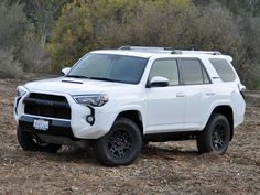 a white toyota suv is parked in the woods