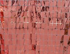 an orange mesh fence is covered with red and pink plastic wraps that have been placed on top of each other