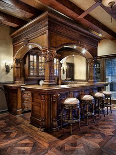 a large kitchen with an island and bar in the center, surrounded by wooden flooring