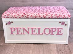 a white toy chest with pink flowers and the word penelope on it