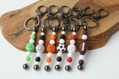 several key chains with different colored balls and soccers on them sitting on a wooden board