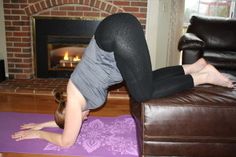 a woman is doing yoga in front of a fire place with her feet on the floor