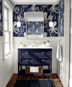 a bathroom with blue and white wallpaper, wooden flooring and an octopus rug