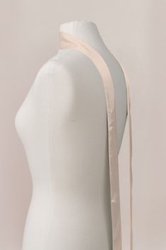 a white mannequin with a beige ribbon around it's neck and shoulder