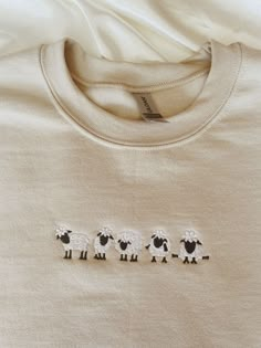 three sheep embroidered on the back of a shirt that is laying on top of a bed