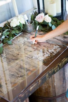 a person writing on a table with flowers and candles