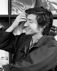 a man sitting at a desk with his hand on his head and looking off to the side