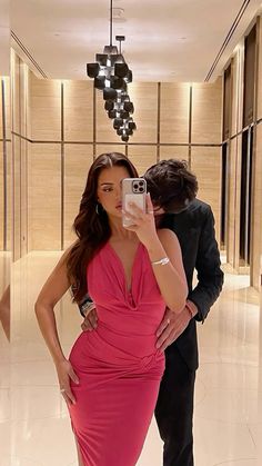 a woman in a pink dress taking a selfie with a man in a suit