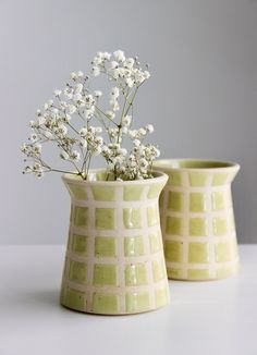 two vases with flowers in them sitting on a table