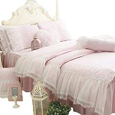 a bed with pink bedspread and pillows on it next to a potted plant